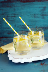 Tasty cool beverage with lemon and thyme, on wooden background
