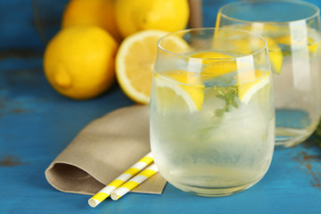 Tasty cool beverage with lemon and thyme, on wooden background