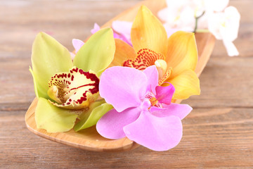 Fototapeta na wymiar Tropical orchid flowers in bowl on wooden background
