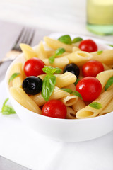 Pasta with tomatoes, olives and basil leaves in bowl
