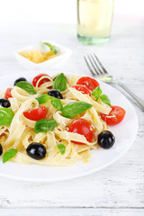 Spaghetti with tomatoes, olives and basil leaves