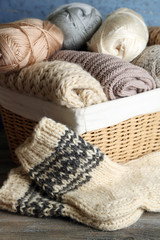 Fototapeta na wymiar Knitting yarn in basket and socks, on wooden background