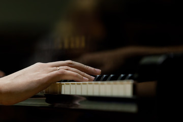Woman's hands on the keyboard of the piano closeup