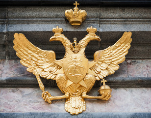 Golden double eagle on stone wall. Coat of arms of Russia