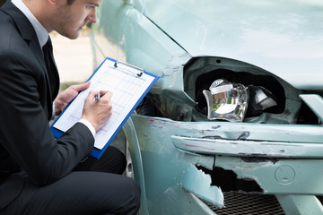 Insurance Agent Examining Car After Accident