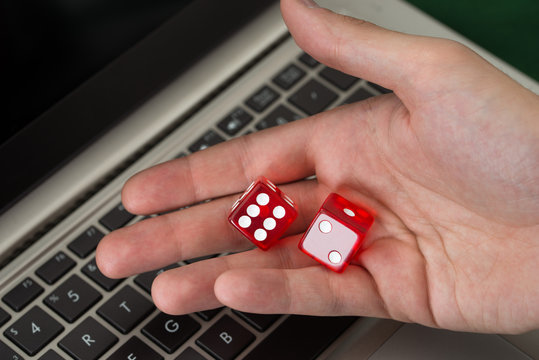 Businessman Holding Red Dices While Using Laptop