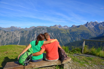 Paar bei Pause auf Bank mit Aussicht beim Bergwandern