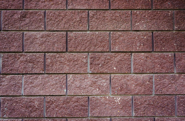 The wall of the large cherry-colored rectangular stones as backg