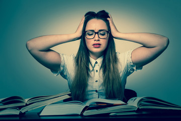 Stressed asian caucasian woman student learning in tons of books