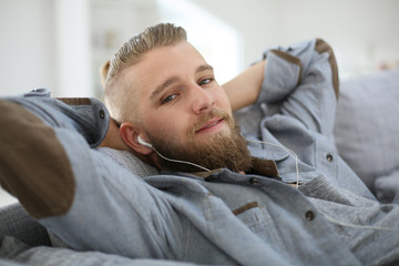 Fototapeta premium Young man relaxing in sofa, listening to music