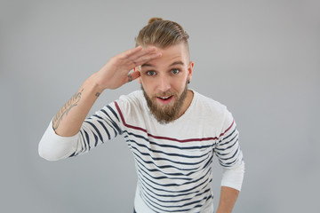 Portrait of trendy guy looking away, hand on forehead