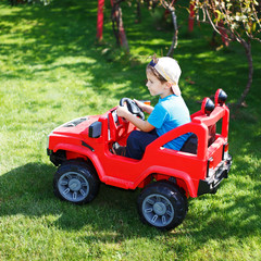 Little boy drive electrical vehicle in garden