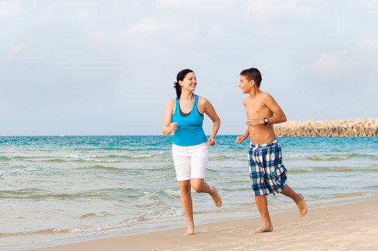 Mother With Her Son Are Running On The Beach And Having Fun