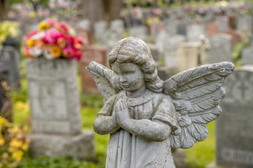 Praying angel in a cemetary with tombstones in the background