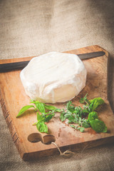 Smelly blue cheese on a wooden rustic table with knife and basil