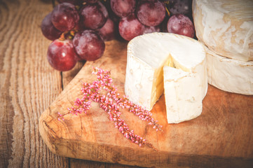 Smelly blue cheese on a wooden rustic table with grape