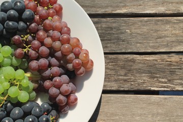 Ripe bunches of grapes on a sunny wooden table