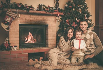Obraz na płótnie Canvas Family near fireplace in Christmas decorated house