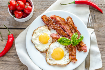 Fried eggs with bacon on the wooden table