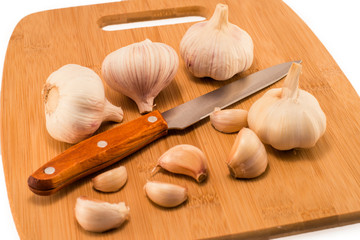Garlic and slices on a cutting board with a knife