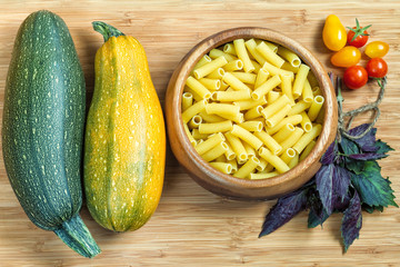 Large fresh zucchini, cherry tomatoes, basil and raw pasta