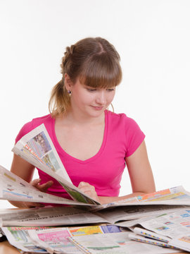 girl thumbs through the newspaper to find right ads