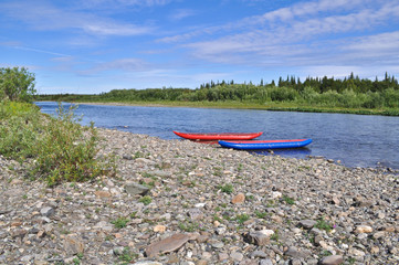 Tourist kayaks at pebble river banks.