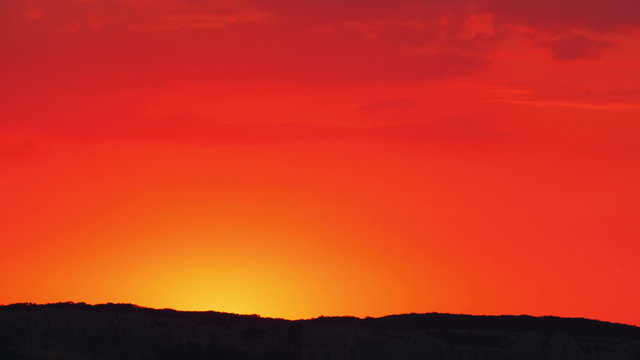 Bright red-orange sunrise behind the mountain