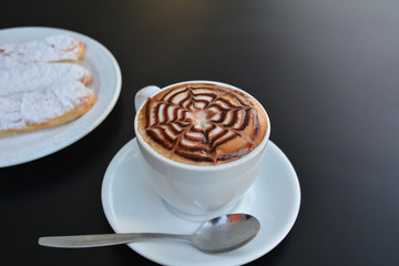 Cappuccino cup and cake on the black background