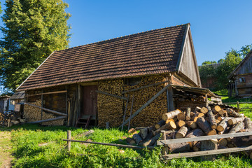 Old wooden farmhouse in the Carpathians with the wood in the yar