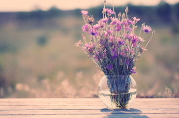 Beautiful wild flowers in vase in field