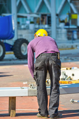 A man in purple blouse and yellow helmet working on construction