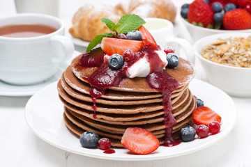 breakfast with pancakes with cream, fruit sauce and fresh berry