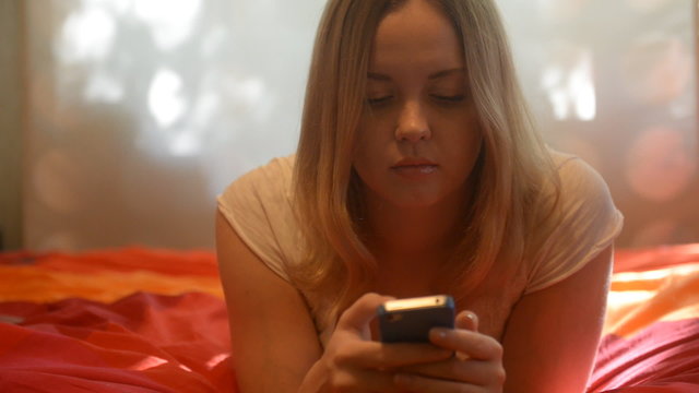 smiling blond girl writing message touch phone sms