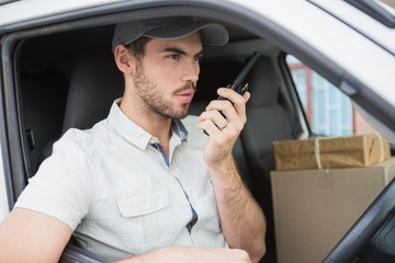 Delivery driver talking on walkie talkie in his van