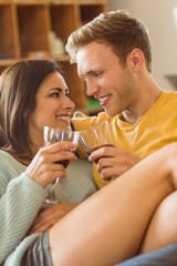 Young couple cuddling on the couch with red wine
