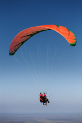 Two paragliders in flight above the land