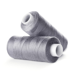 Two reels of gray thread on white background