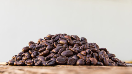 Close up of roasted coffee beans laying on a pile of old wood