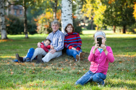 Happy family is on autumn park making pictures on phone