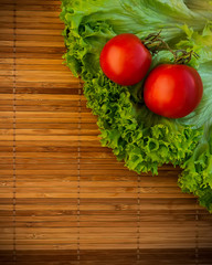 Fresh salad and tomatoes on wooden surface