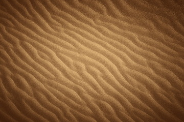 Golden wavy beach sand texture with vignette.