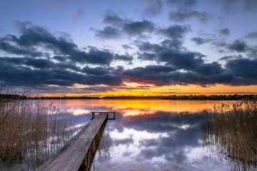 Purple Sunset over Tranquil Lake with Reed and Wooden Jetty