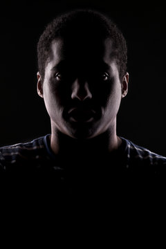 african man with the face in shadow on a dark background