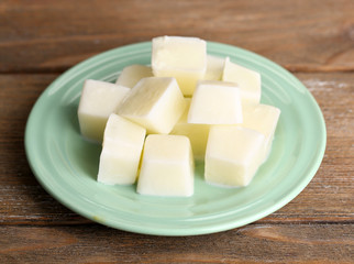 Milk ice cubes on plate on wooden background