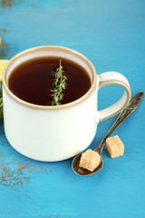 Cup of tasty herbal tea with thyme on blue wooden table