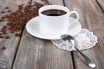 Cup of coffee and coffee beans on napkin on wooden background
