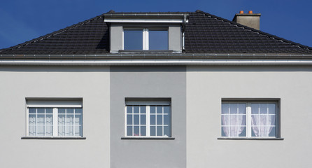 Modernisierte Fassade eines Altbaus mit Schleppgaube in grau