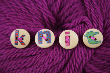 Lettered buttons spell the word knit sewn to a ball of wool