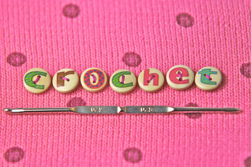 crochet spelled in lettered buttons on a pink wool background